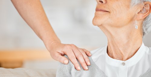 Bilde av en som holder en hånd på skulderen til en eldre kvinne